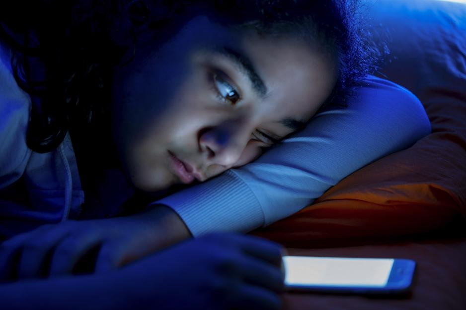 Woman in the dark with the glow of a cell phone illuminating her face