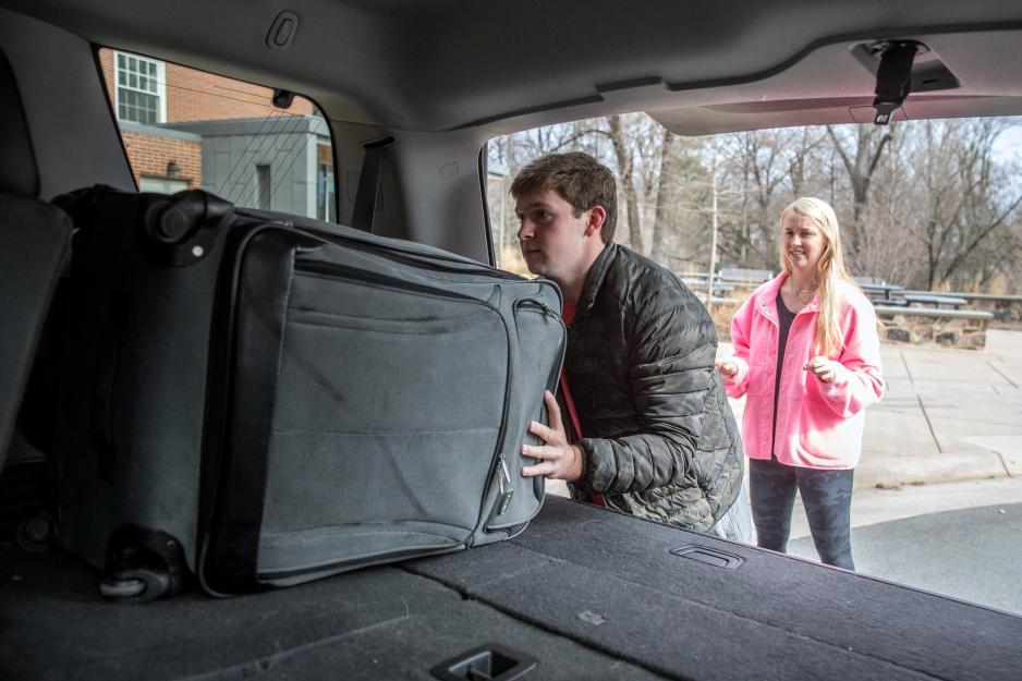Rob Jolly and Reese Quillian  put luggage into back of vehicle 
