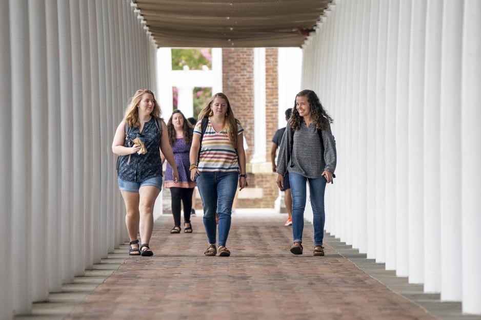 Students walking on a sidewalk lined with white columns