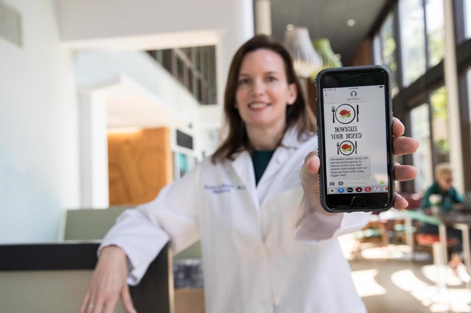 Susan Blank holds her phone out with a text message image visible that says Downsize your Disease