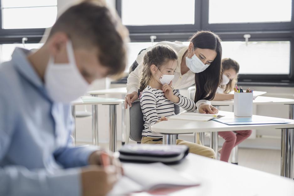 Teacher helping a little girl at her desk