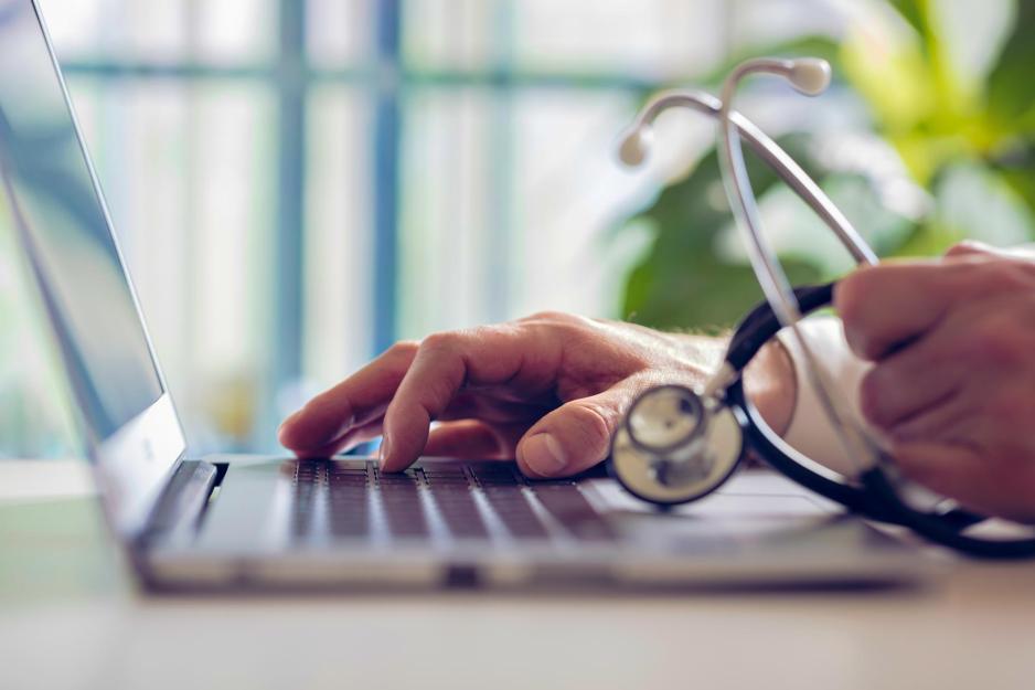 doctor working on a computer and holding a stethoscope 