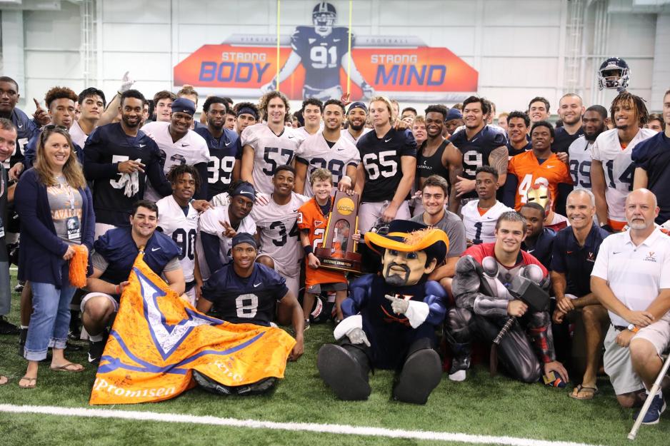 The UVA football program poses with children for a picture