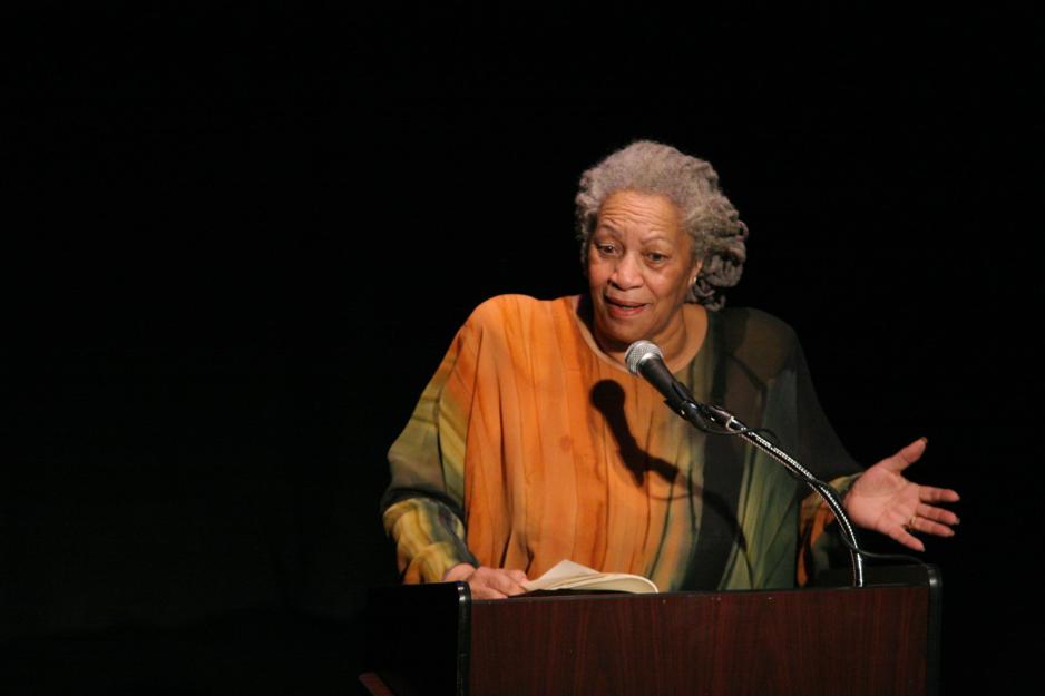 Toni Morrison speaking into a microphone on stage at a podium