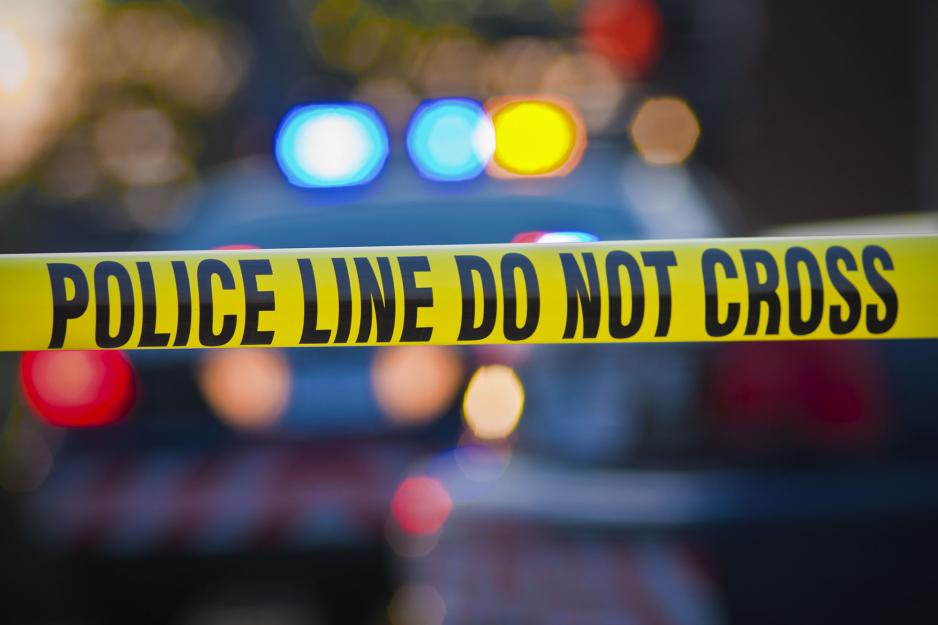 Blurred emergency lights with police tape that reads: Police line do not cross