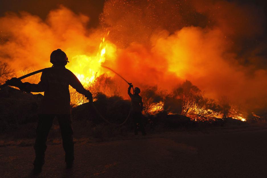 silhouettes of  Firefighters putting out a fire