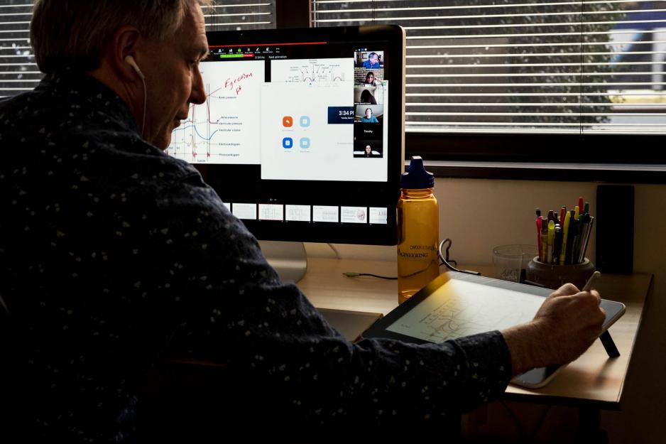 Professor during a zoom class using a tablet to show work to his students