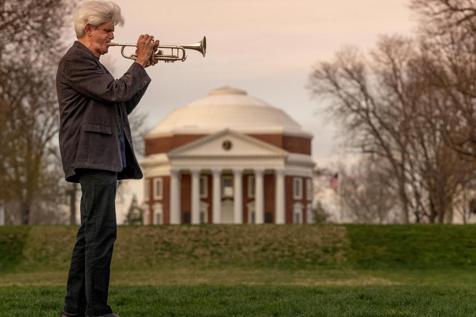 Man standing on the lawn playing a trumpet in front of the Rotunda