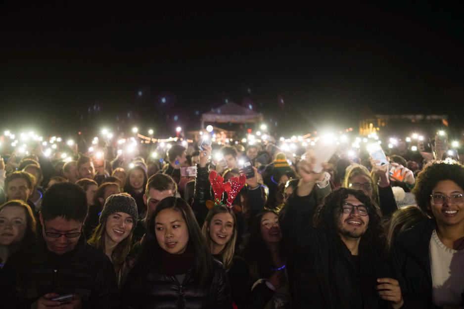 Hundreds of people on the Lawn holding their cellphones in the air with their flashlights on for a concert