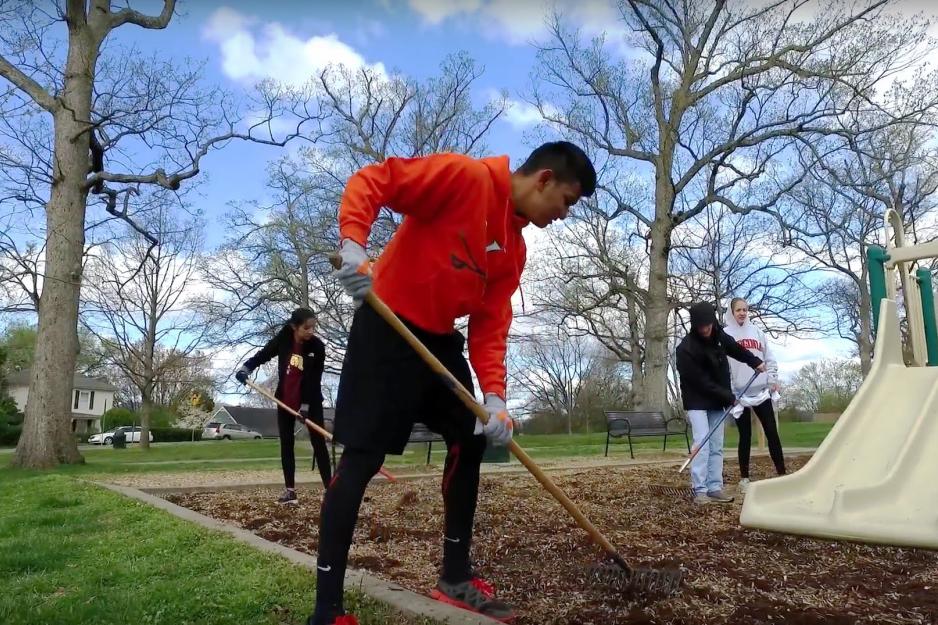 Adults using rakes to smooth out mulch