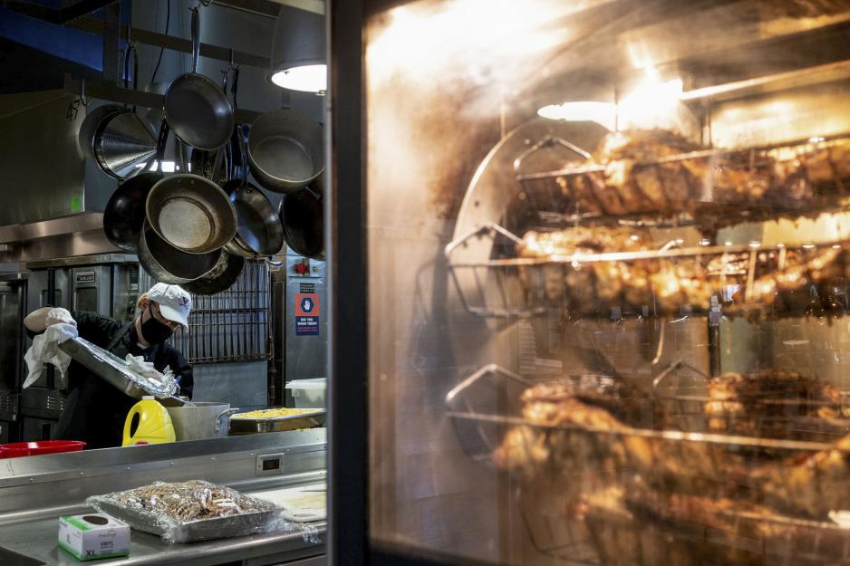 Rotisserie turkey in Rotisserie while UVA service member works in the background   