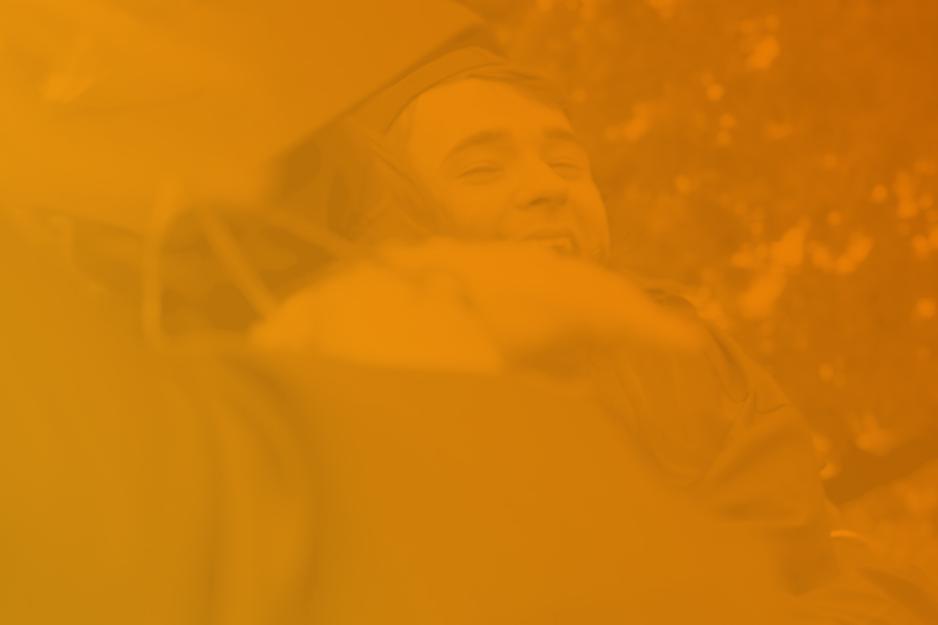 Graduates hugging with an orange overlay
