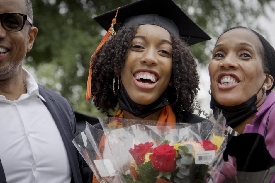 Graduate taking a picture with their family while holding flowers