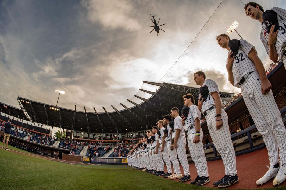 A fisheye look up at the U V A baseball team as they stand lined up for the national anthem and a heliocopter flys over