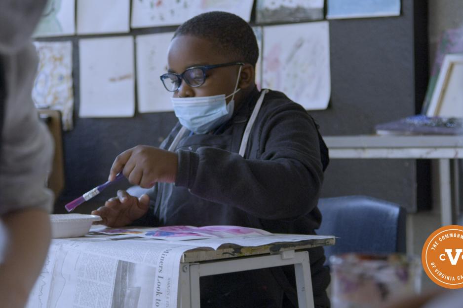 Student painting a picture with purple paint