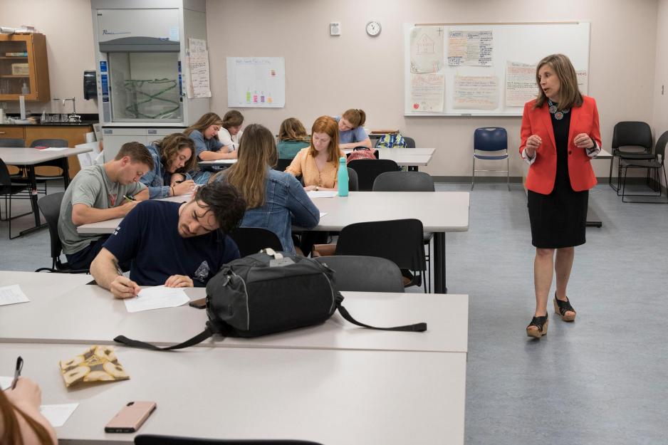 Jennifer Pease walking around a classroom while students are writing