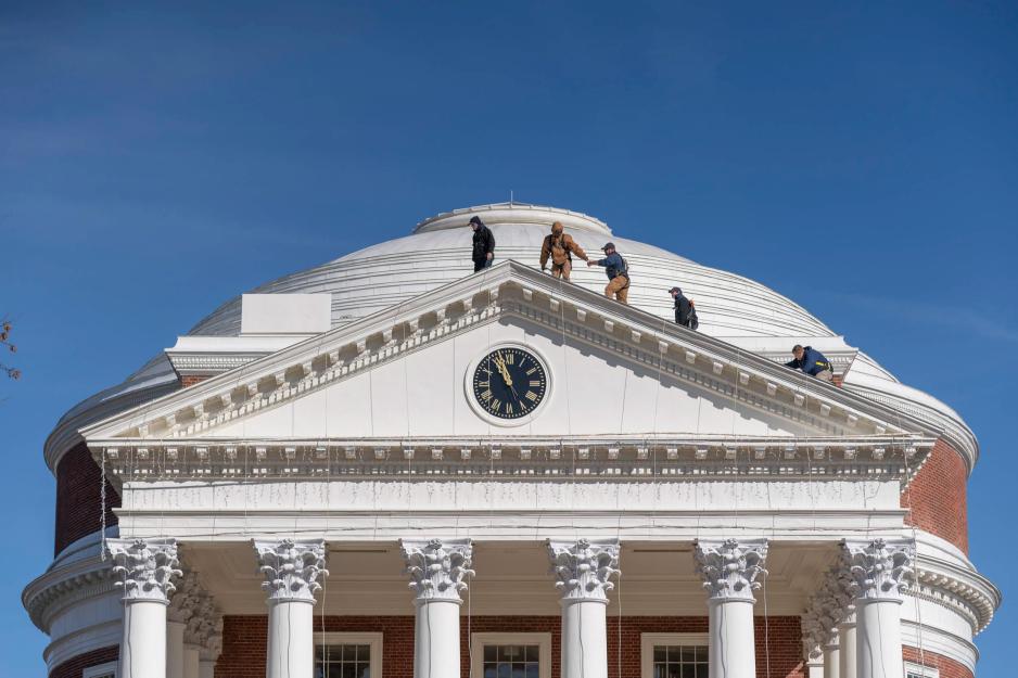 Men on top of the Rotunda hanging icicle light on the roofs edge