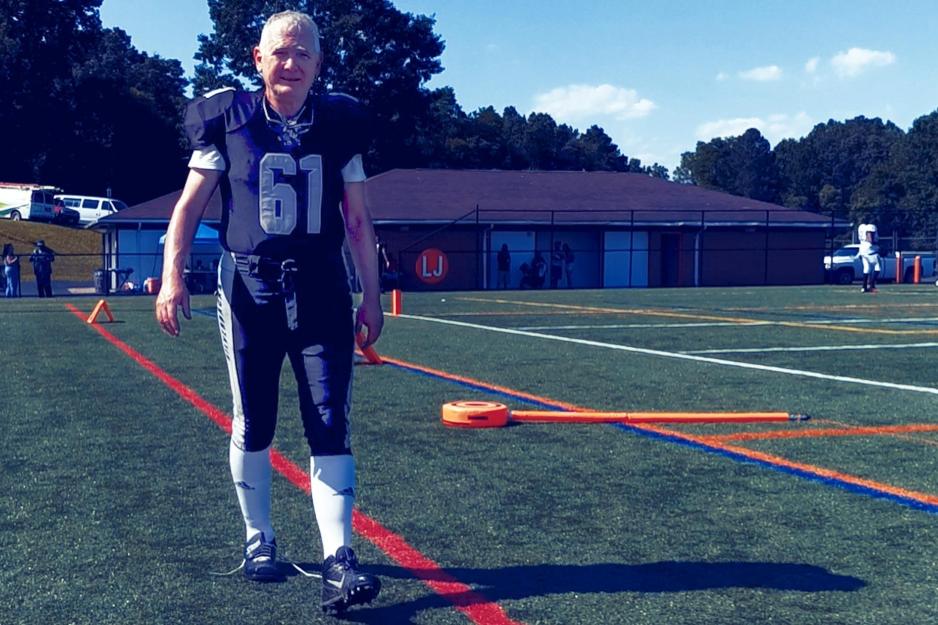 Lynch in a football uniform walks on a football field