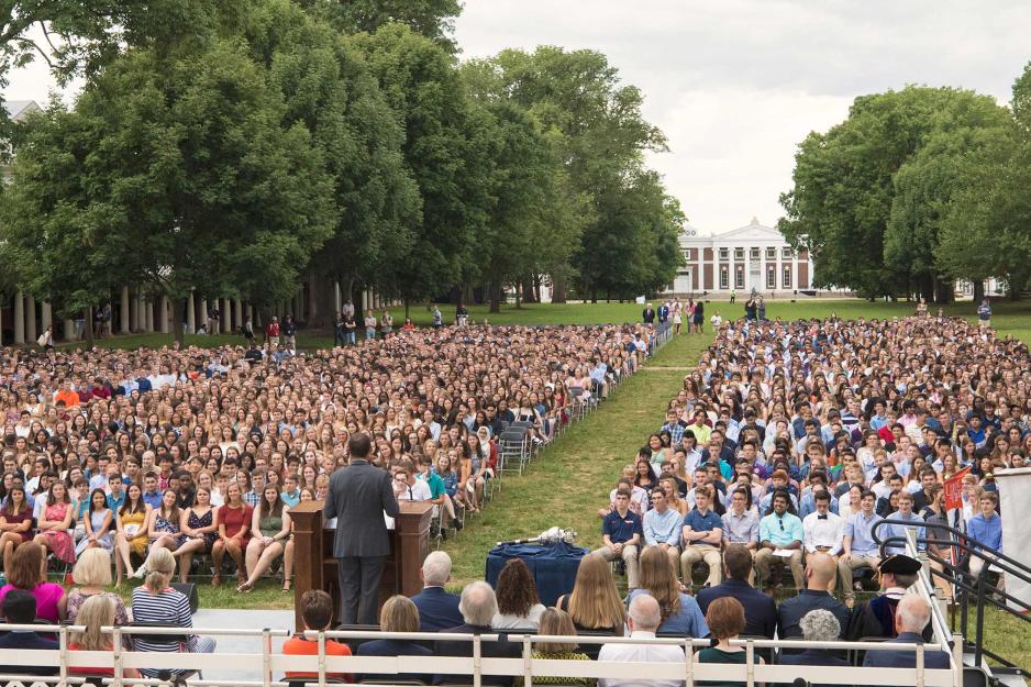 President Ryan stands at a podium talking to the Lawn full of students sitting in chairs