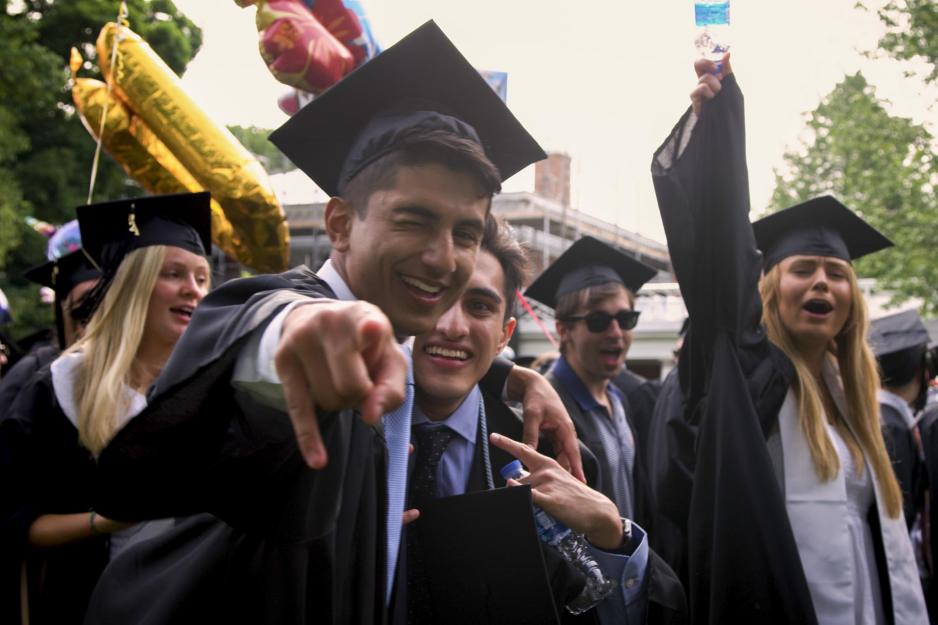 Graduates pose for a picture together pointing at the camera