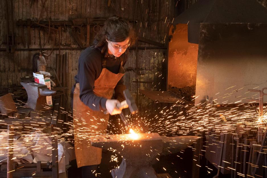 Mira du Plessis using a hammer to create something in the Blacksmith shop
