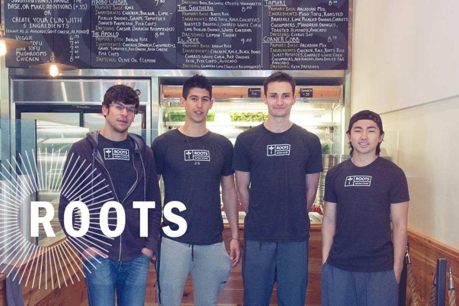  Four students stand together for a group picture with shirts that say Roots