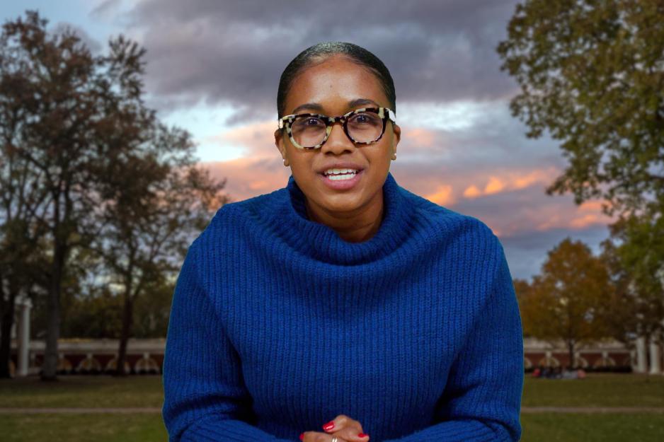 Woman with glasses sitting at a news anchor desk