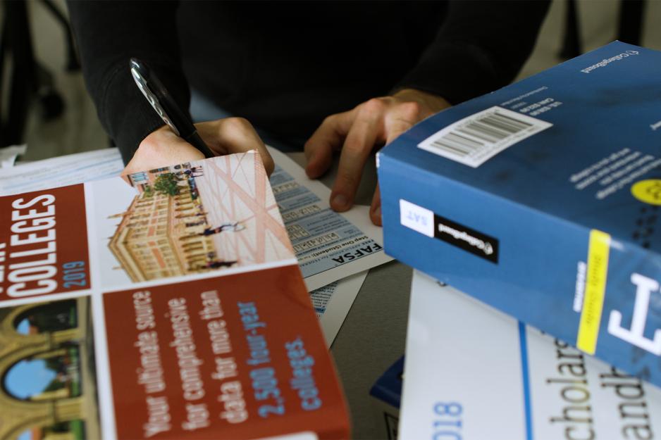Person filling out a FAFSA form with books around them