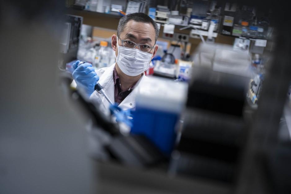 Tsuyoshi Miyake looking at the camera while working in the lab