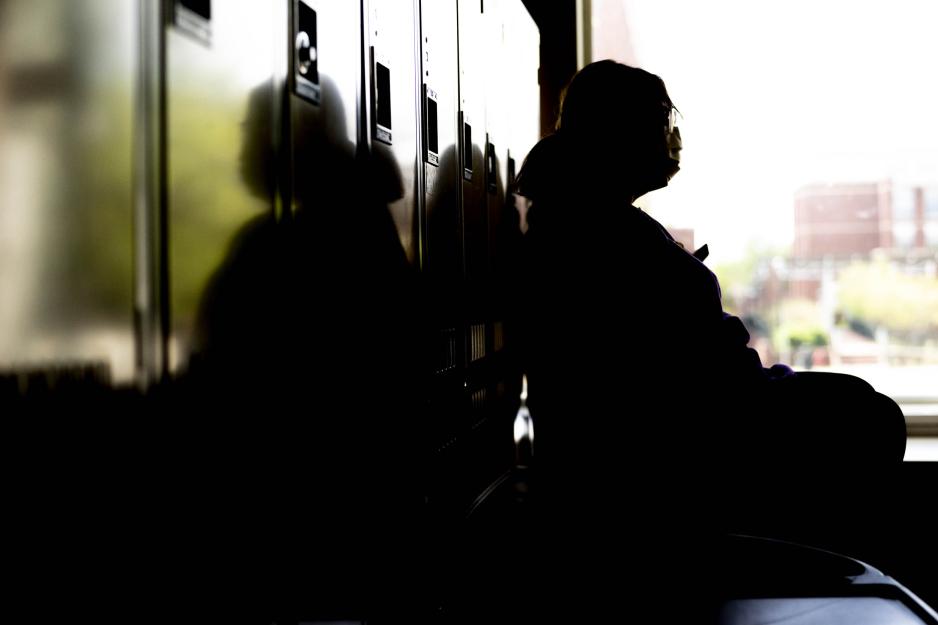 Person sitting next to lockers staring off into the distance