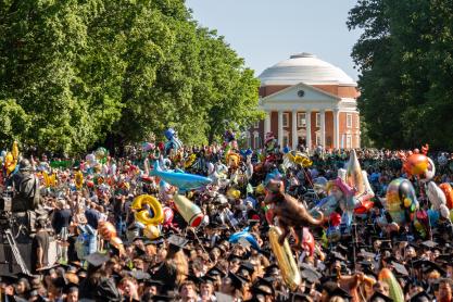 A crown of UVA graduates during Final Exercises on the Lawn holding graduation ballons