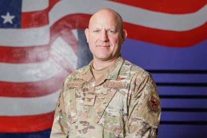 U.S Air Force Col. Cary Mittelmark stands in front of a mural of the U.S. Flag
