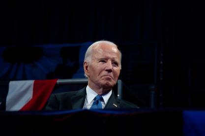Former President Joe Biden sitting on stage at a conference