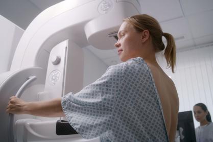 Portrait of a woman wearing patient gown and undergoing her mammogram test.