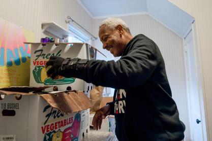 Candid portrait of David Shackelford opening a box to distribute groceries.