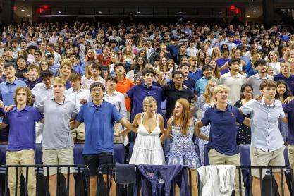 Portrait of UVA Class of 2029 students link arms to sing “The Good Old Song.”