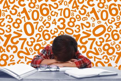 student laying head on desk surrounded by numbers and books