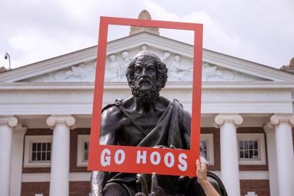 Portrait of the UVA Homer Statue in a portable red paper frame with 'Go Hoos' written on it.