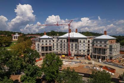 An aerial view of the Kimpton hotel near Darden as it is being constructed. A large crane stands in the foreground near some trees. 