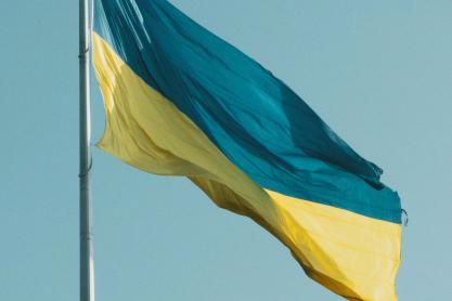 The teal and yellow flag of Ukraine flies in the wind on a clear day