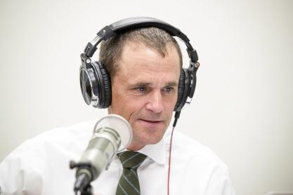 University of Virginia President Jim Ryan wearing headphones speaks into a microphone