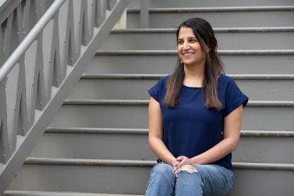 UVA associate professor Rupa Valdez sits on a flight of stairs, smiling