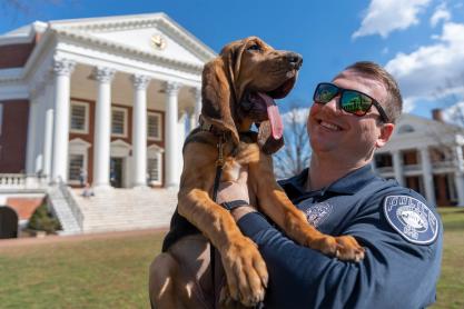 Officer Logan Moore holding Maggie, the bloodhound, on the Lawn by the Rotunda