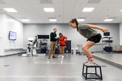 A girl is jumping off a stool.