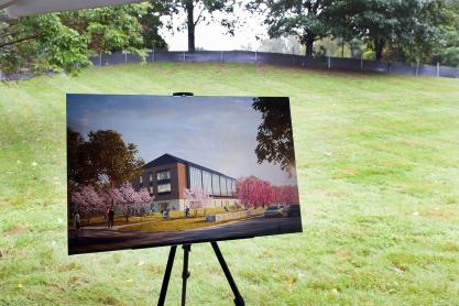Digtial rendering of a new building sits on an easel in an empty green space