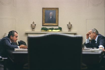 President Lyndon B. Johnson, right, and Richard Nixon, left talk across from each other at a table