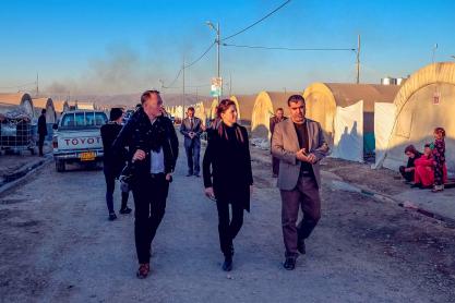 John Kluge, left, and Christine Mahoney walk with an interpreter while visiting a Syrian refugee camp in Iraqi Kurdistan. 