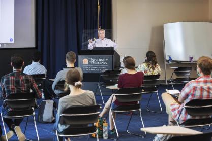 Dr. Robert Powers speaking to a group of students from a podium