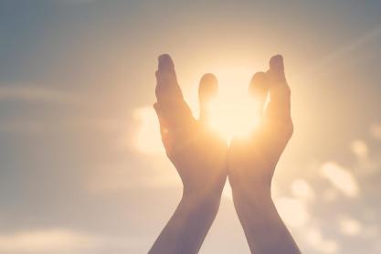 Person holding their hands up to hold the sun