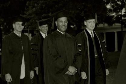 Black and white photo of Walter Ridley, front, walking with graduates on the Lawn during Final Exercies